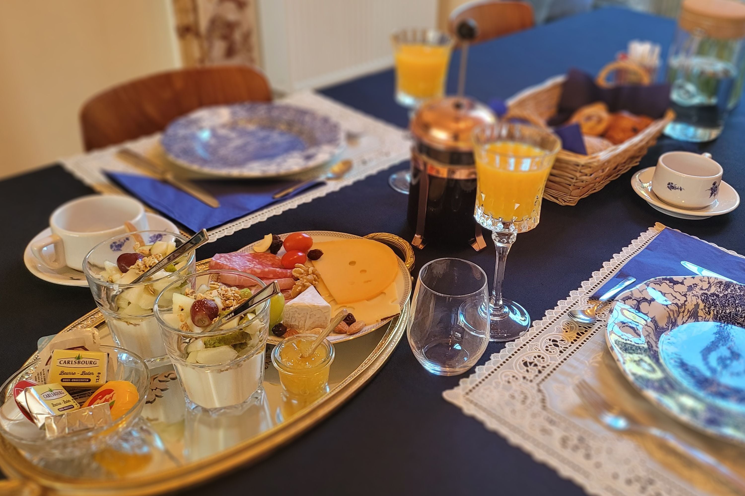 Un desayuno con una variedad de alimentos, como queso, frutas y pasteles, presentados en una bandeja.