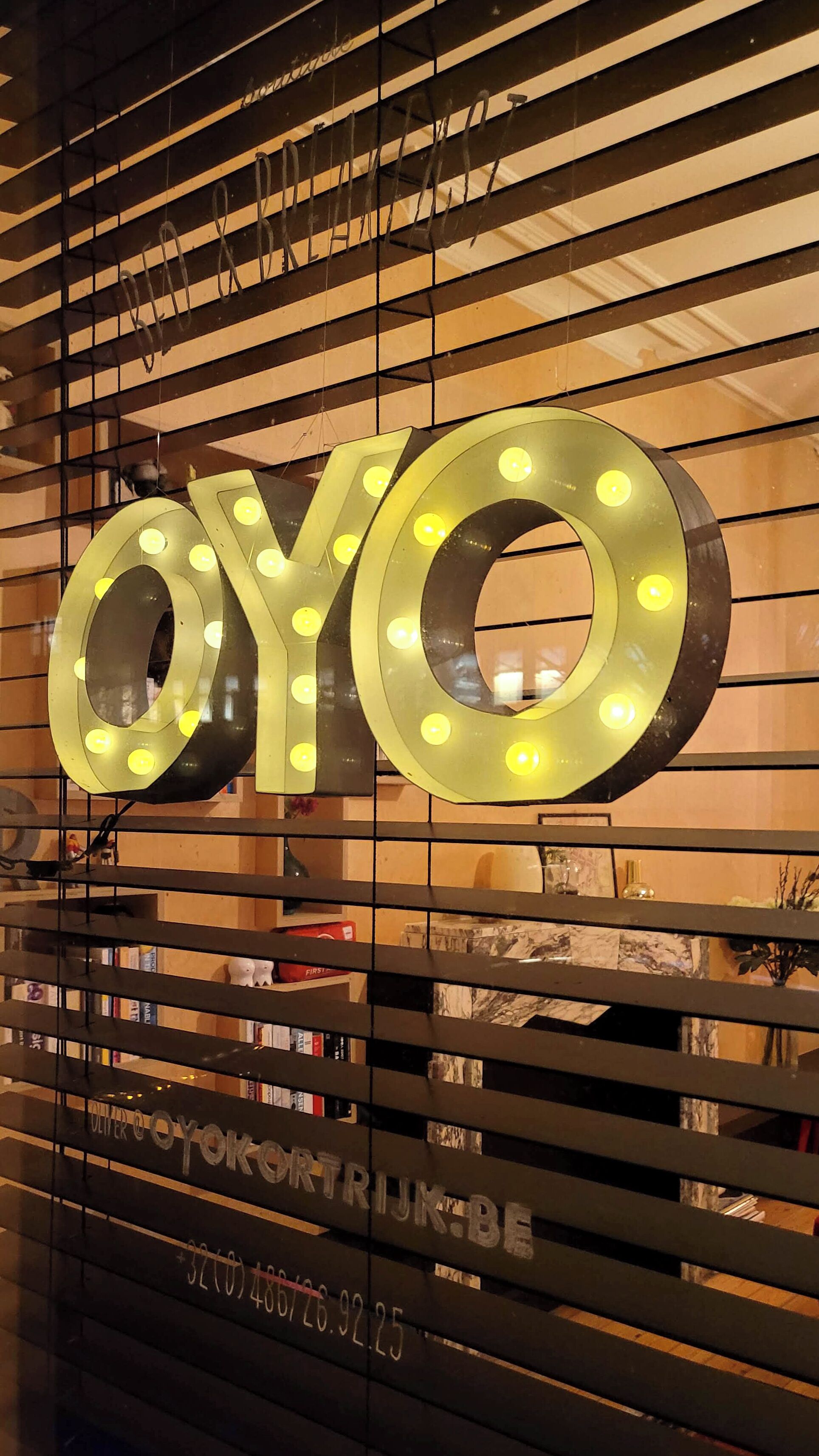 Une enseigne avec des lettres lumineuses formant le mot « OYO » sur un fond de stores horizontaux.