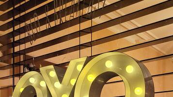 Une enseigne avec des lettres lumineuses formant le mot « OYO » sur un fond de stores horizontaux.