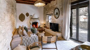Una sala de estar acogedora con chimenea de piedra, un televisor y un sillón de mimbre.