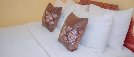 A neatly made bed with white linens and two decorative pillows with a floral pattern.