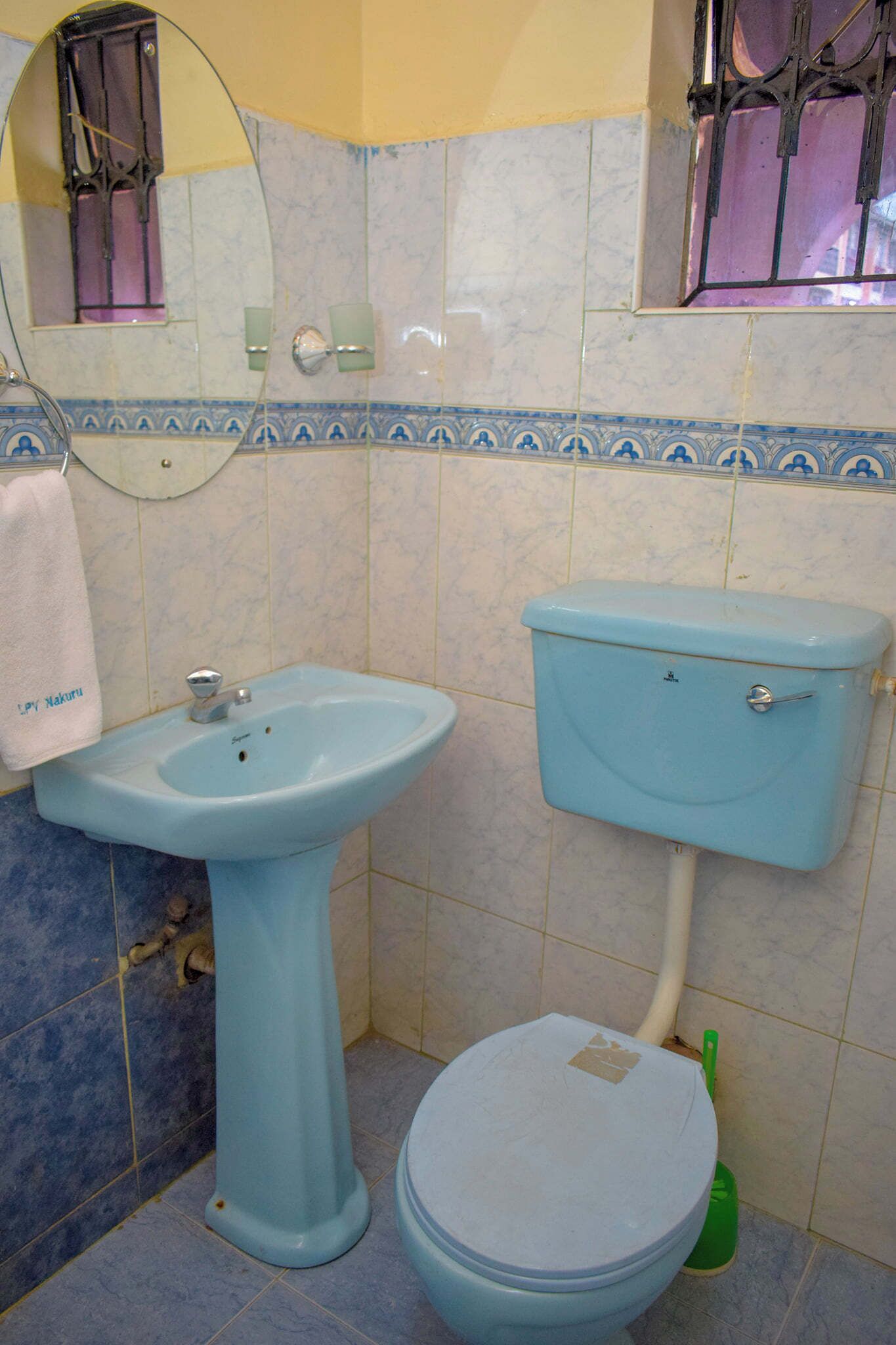 A bathroom with a pedestal sink, toilet, and a mirror.