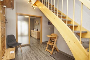 A wooden staircase with a cushioned handrail, a black chair, and a wooden chair with a tray. - Vacation home Strandfeeling Glowe - House in a great location with garden, terrace and (Glowe)