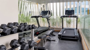 A modern gym with treadmills, dumbbells, and a bench. - Bloom Hotel - BKC Kalina (Mumbai)