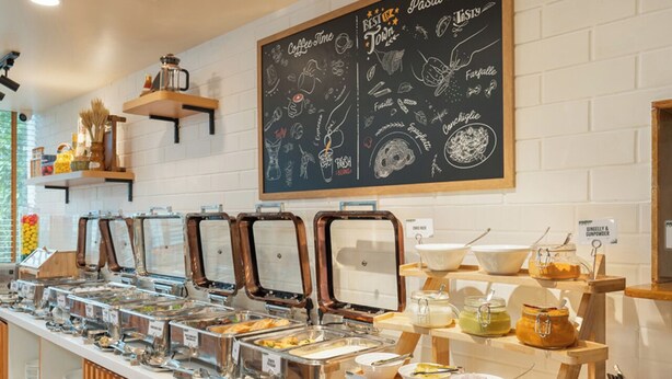 A buffet setup with various food stations, a chalkboard menu, and a coffee station. - Bloom Hotel - BKC Kalina (Mumbai)