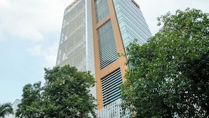 A tall, modern building with a glass facade and a central vertical section with horizontal slats. - Bloom Hotel - BKC Kalina (Mumbai)