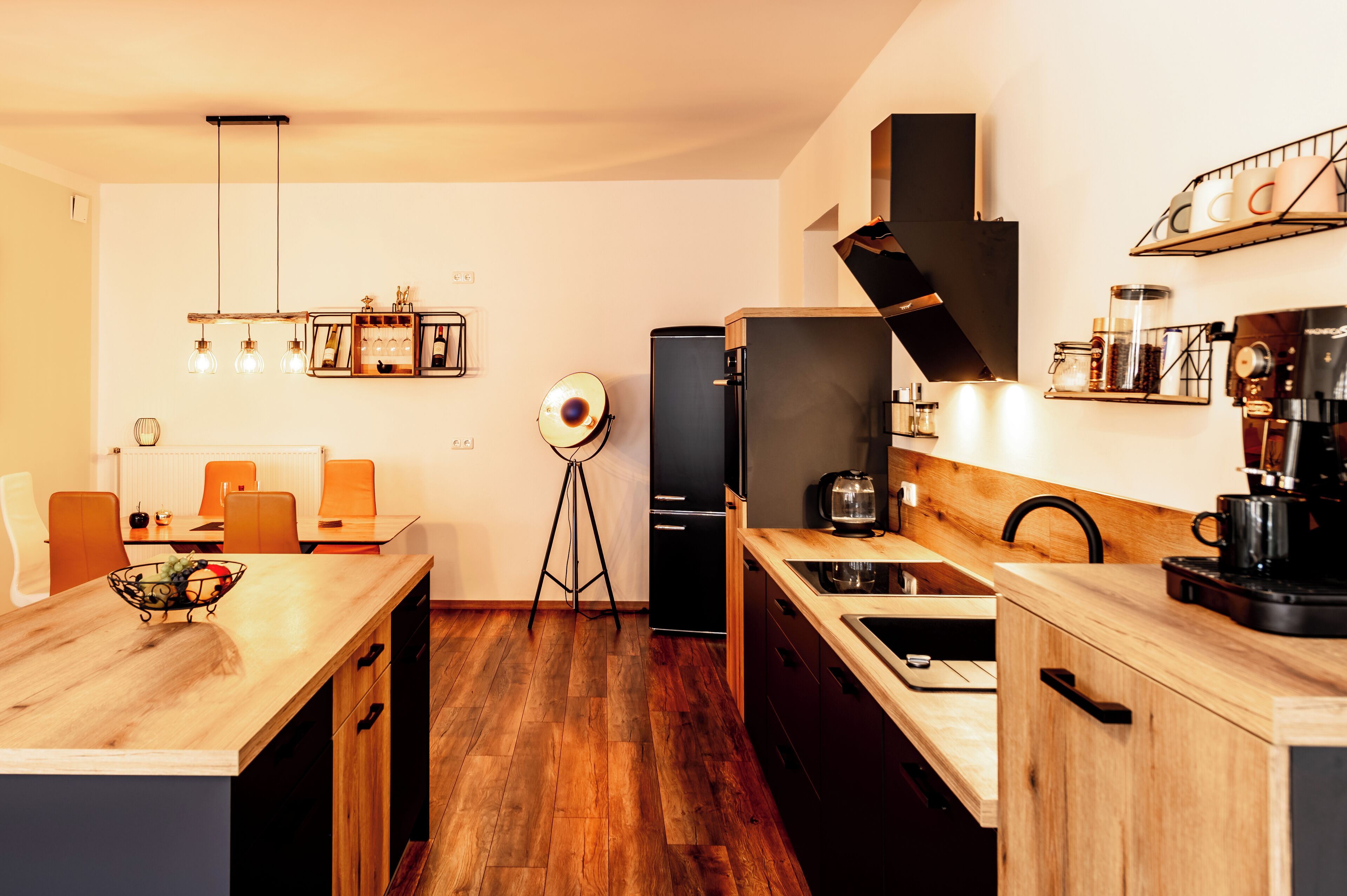 Una cocina moderna con encimeras de madera, un refrigerador negro y una cafetera.