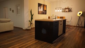 Eine moderne Küche mit einer zentralen Kochinsel, Holzboden und einem Essbereich mit einem weißen Stuhl.