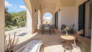 Eine Terrassesituation mit Tisch und Stühlen, einer gepolsterten Sitzecke und Blick auf die umliegende Landschaft.