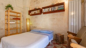 Une chambre à coucher avec un lit, des étagères en bois remplies de livres, un radiateur et une chaise.