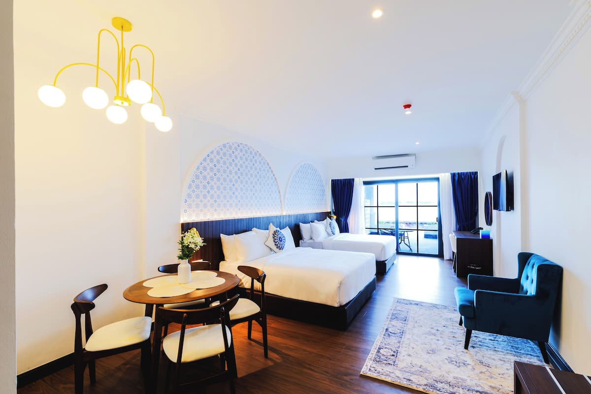 Une chambre d’hôtel avec un grand lit, un bureau avec des chaises, une table à manger, un téléviseur et un lustre.