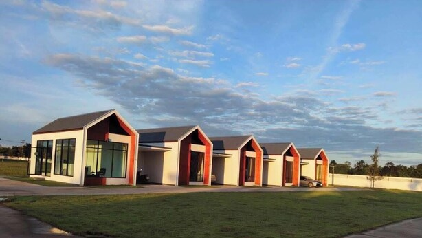 A modern resort with a series of connected buildings, a well-maintained lawn, and a clear sky. - The Orange Grand Resort (Det Udom)