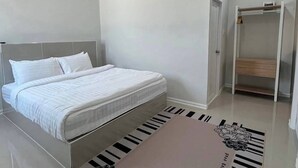 A modern bedroom with a bed, a built-in wardrobe, and a flat-screen TV mounted on the wall. - The Orange Grand Resort (Det Udom)