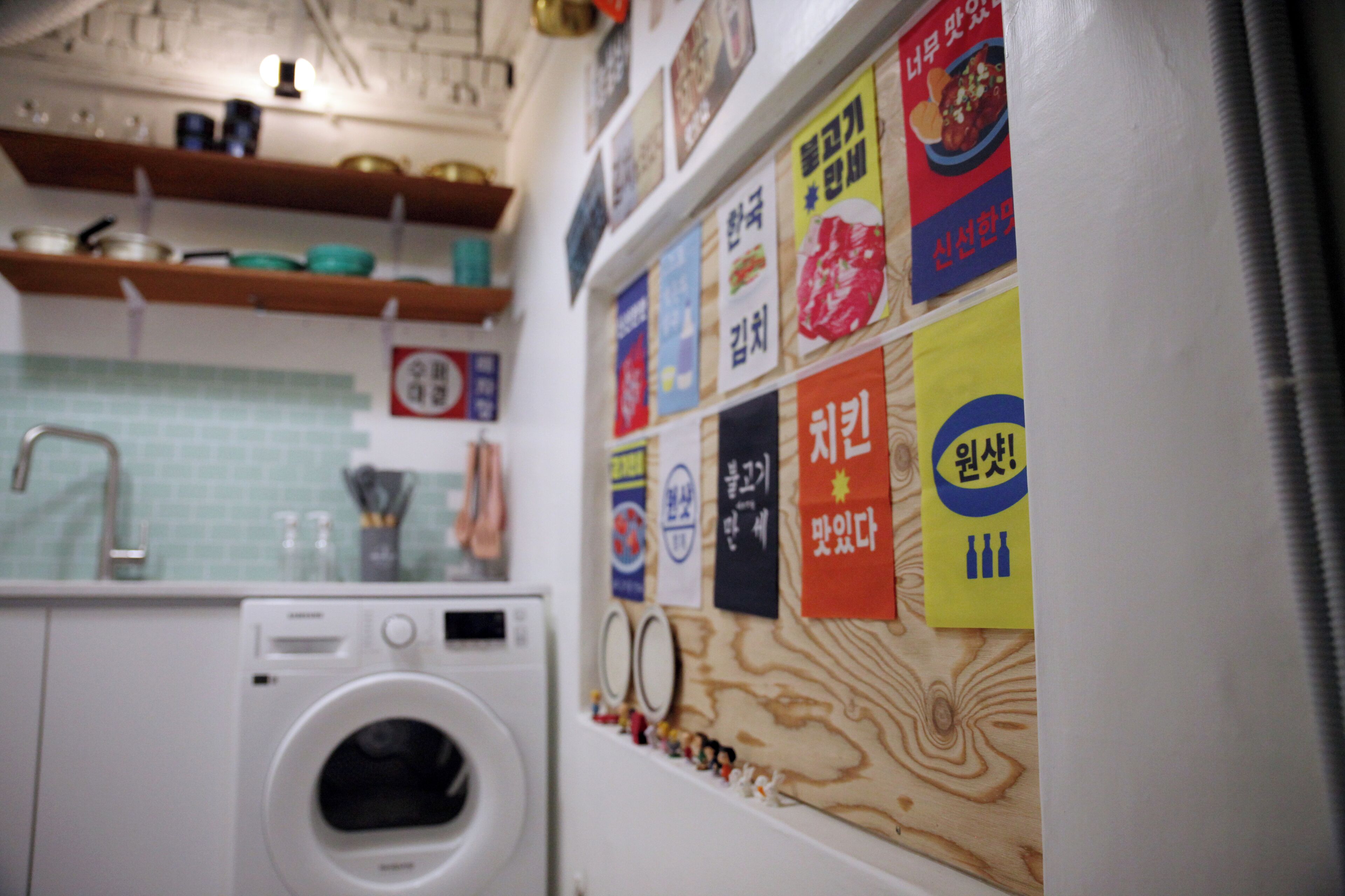 A laundry area with a washing machine, a sink, and various kitchen items on shelves.