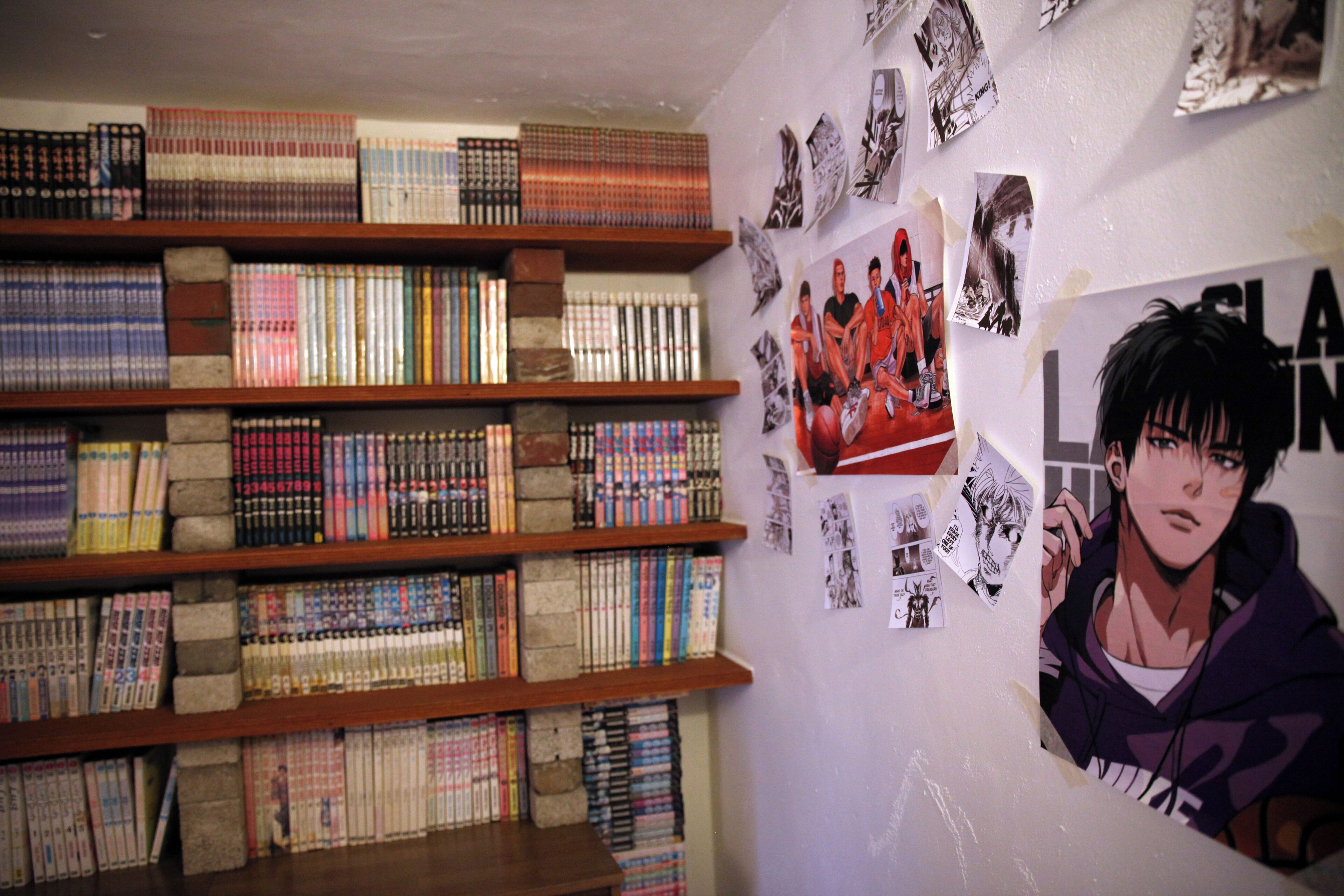 A room with a bookshelf filled with books, a poster on the wall, and a window.