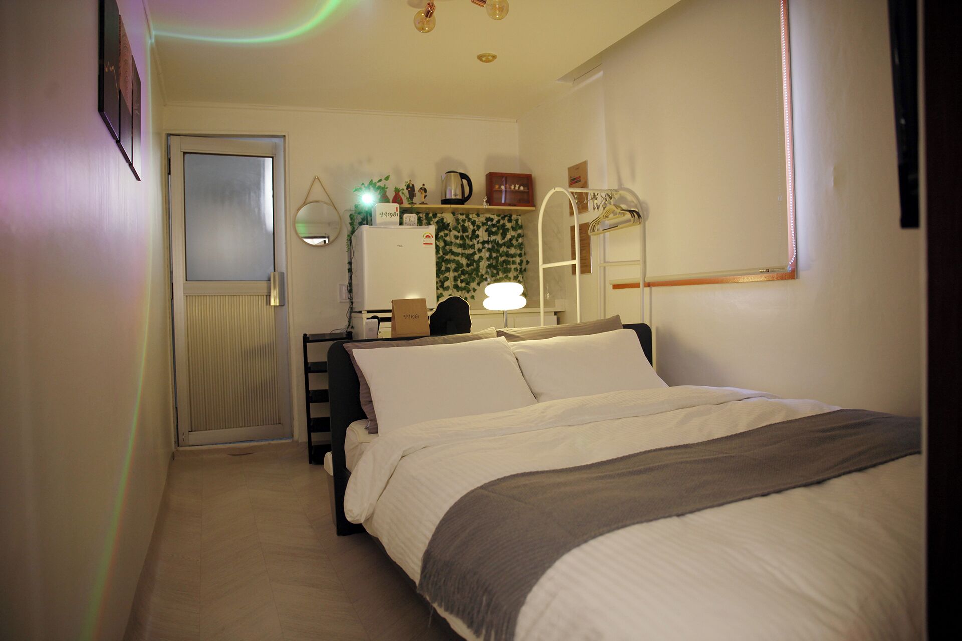 Ein Schlafzimmer mit Bett, Schreibtisch, Stuhl, Spiegel und Fenster.