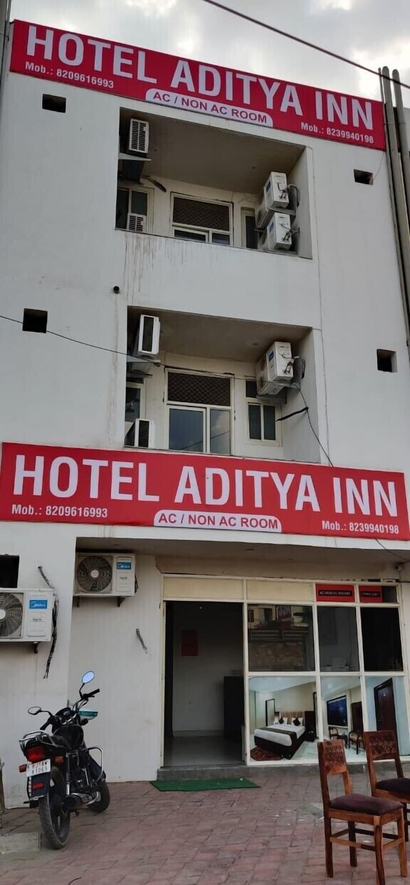 Rakennuksessa on kyltti, jossa lukee Hotel Aditya Inn, ja siellä on sekä ilmastointilaitteilla varustettuja että tavallisia huoneita.