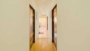 A corridor with a polished floor and doors on either side. - Hotel Aditya Inn (Jaipur)