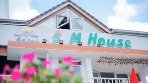 Ein Gebäude mit dem Schild 'M House' und einem Logo über dem Eingang.