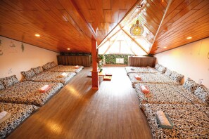 A room with a sloped ceiling, wooden flooring, and multiple beds with patterned bedding. - Homestay 3M House (Cam Ly - Da Lat)
