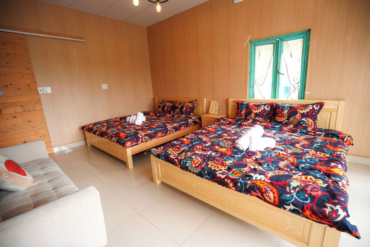 A room with two wooden beds, a white sofa, and a window with curtains.