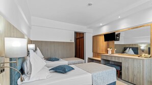 A modern hotel room with two beds, a desk, a TV, and a mirror.