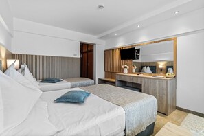 A modern hotel room with two beds, a desk, a mirror, and a television.