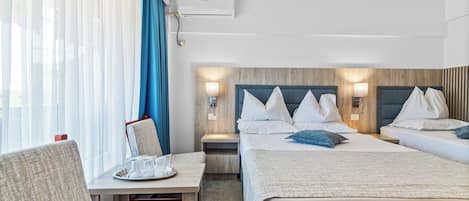 A hotel room with two beds, a desk, a chair, and a window with curtains.