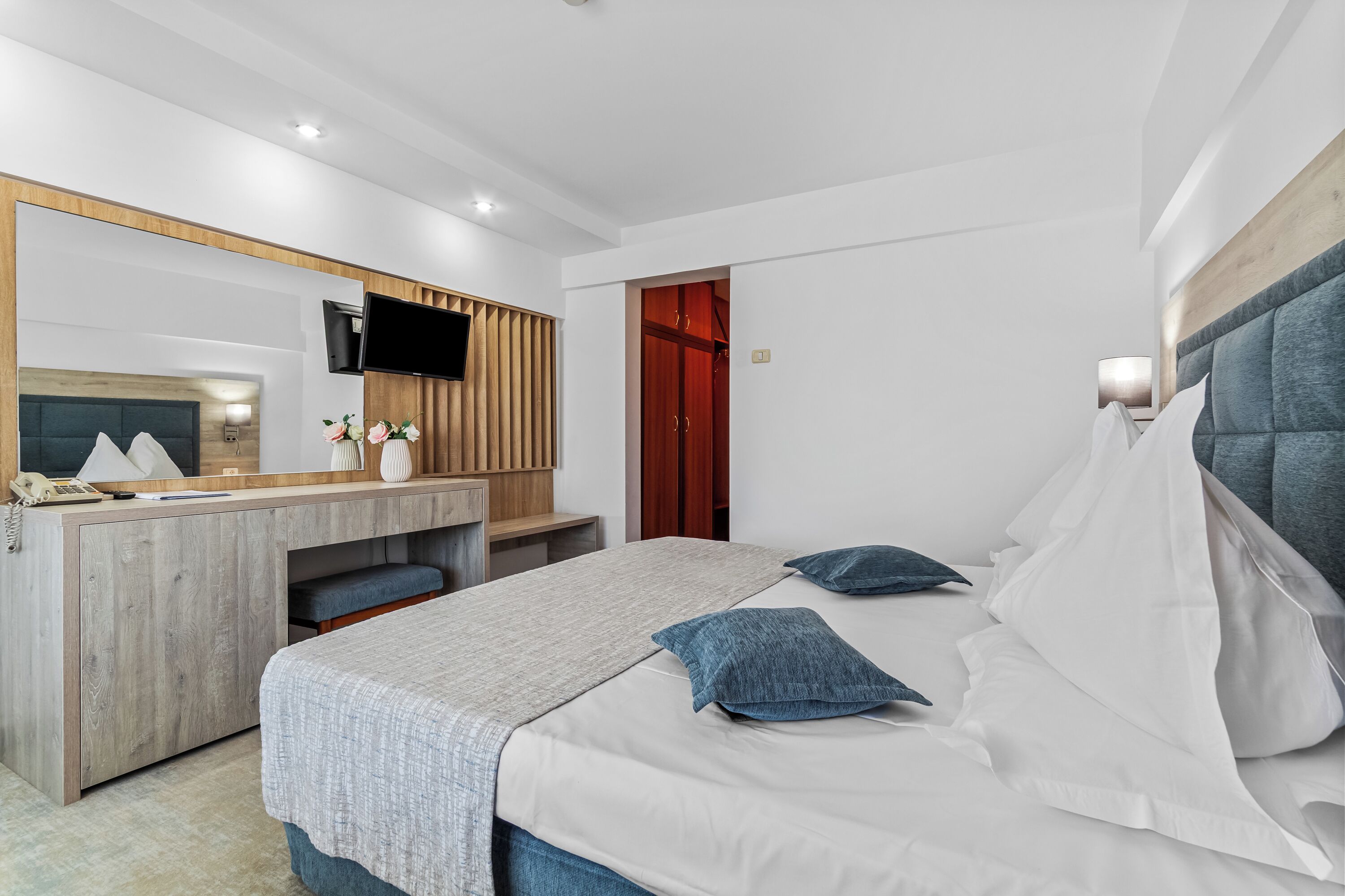 Une chambre d’hôtel moderne équipée d’un lit, d’un bureau, d’un miroir et d’une télévision.
