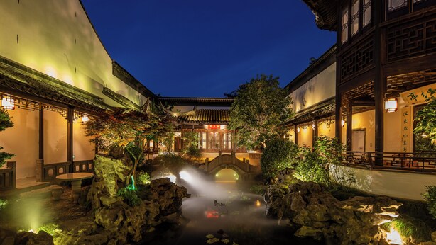 A traditional courtyard with a stone bridge, potted plants, and a small pond. - Suzhou Shantang Scholars Boutique Hotel (Suzhou)