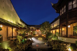 A traditional courtyard with a stone bridge, potted plants, and a small pond. - Suzhou Shantang Scholars Boutique Hotel (Suzhou)