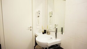 A bathroom with a white sink, a mirror, and a hairdryer mounted on the wall. - Independent two-room apartment Apartment M39 (Gabicce Mare)