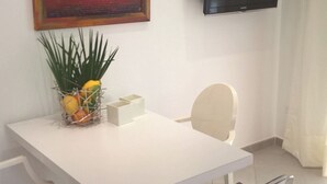 A modern dining area with a white table, clear chairs, a potted plant, and a flat-screen TV mounted on the wall. - Independent two-room apartment Apartment M39 (Gabicce Mare)