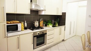 A modern kitchen with white cabinets, a microwave, stove, and various kitchen items on the counter. - Independent two-room apartment Apartment M39 (Gabicce Mare)
