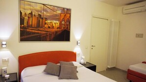 A hotel room with a bed, a nightstand, a lamp, a painting of a cityscape, and a radiator. - Independent two-room apartment Apartment M39 (Gabicce Mare)