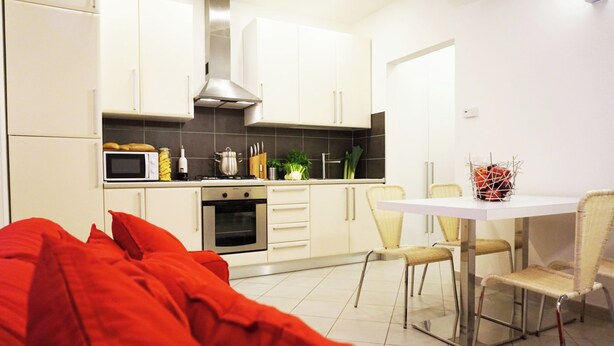 A modern kitchen with white cabinets, a microwave, and a dining area with a table and chairs. - Independent two-room apartment Apartment M39 (Gabicce Mare)