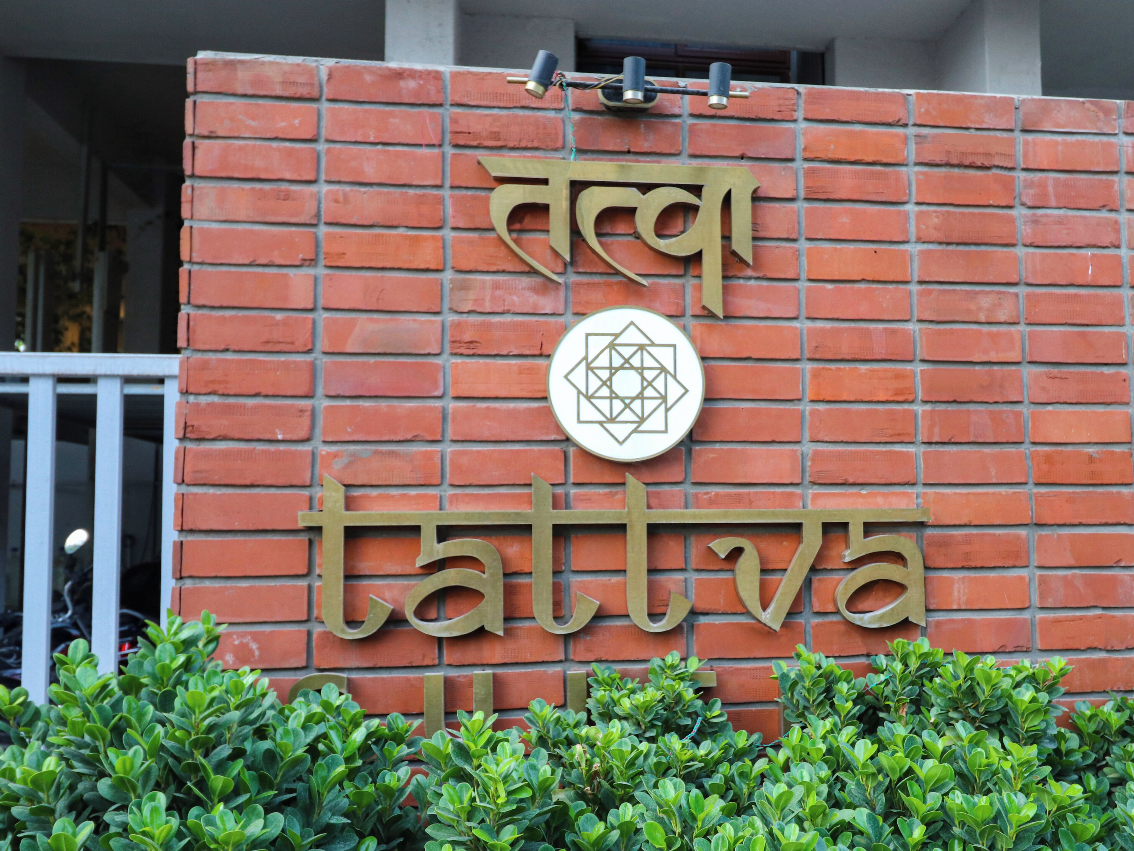 A brick wall with a sign that reads "Tattva" and a geometric symbol.