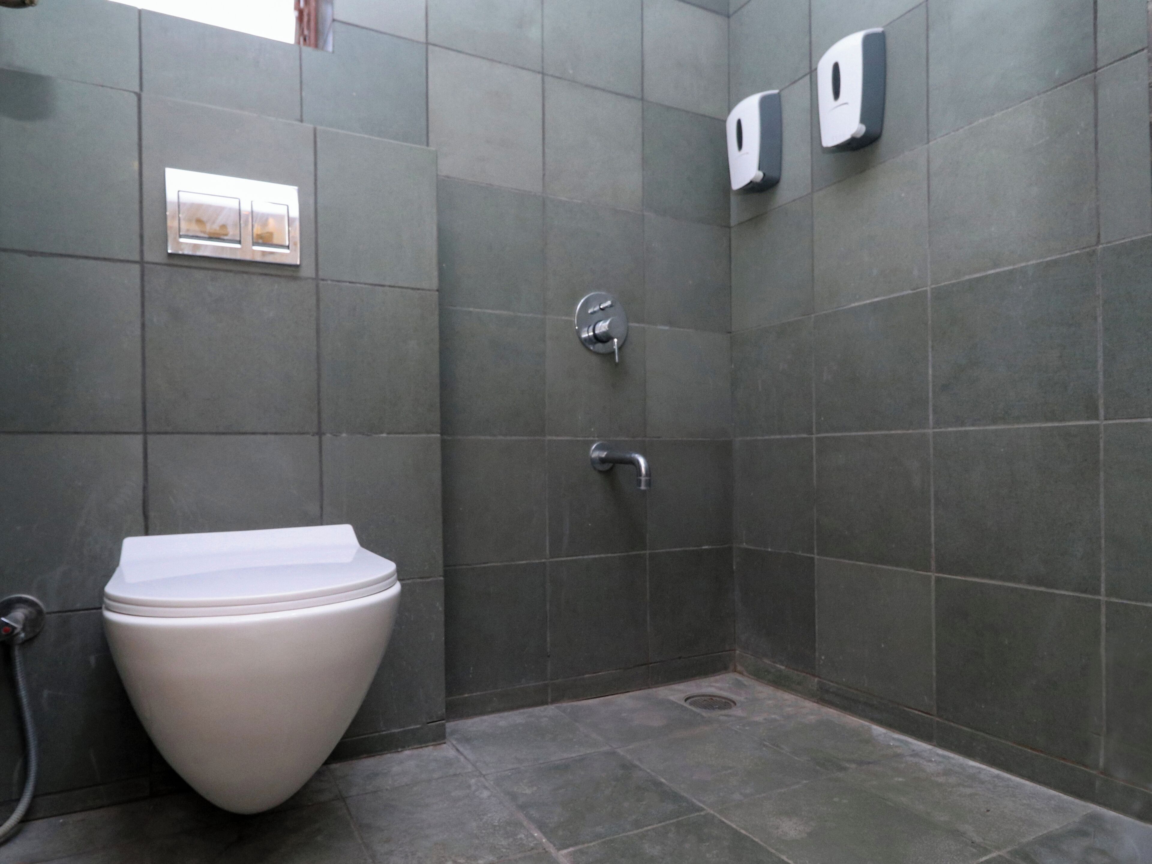 A modern bathroom with a toilet, a hand dryer, and a paper towel dispenser.