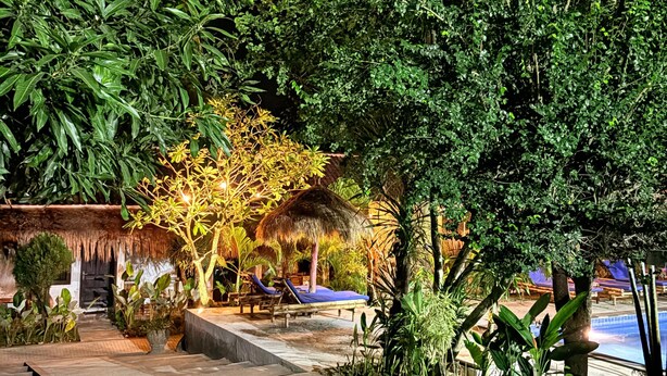 A tropical resort with a pool, lounge chairs, and thatched-roof structures. - Alfa Kuta (Kuta)