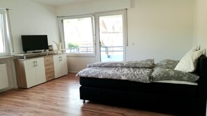 Een moderne woonkamer met een bank, een televisie en een schuifdeur naar een buitenruimte.