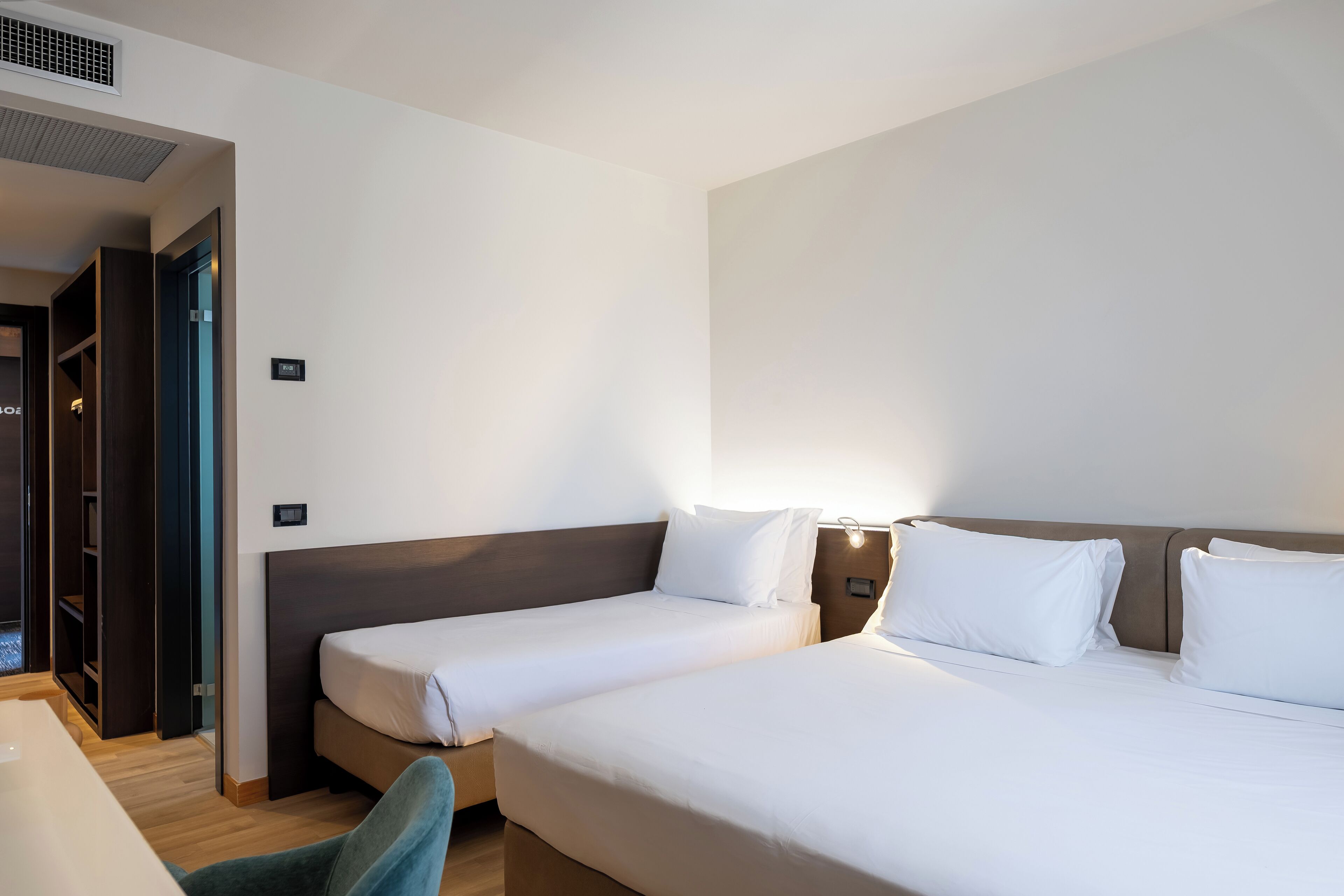 A hotel room with two beds, a desk, and a wardrobe.
