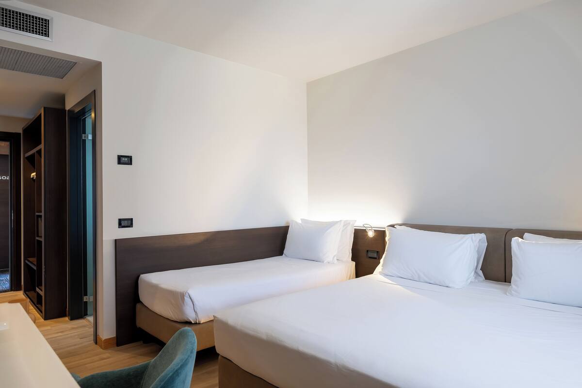 A hotel room with two single beds, a desk, and a wardrobe.