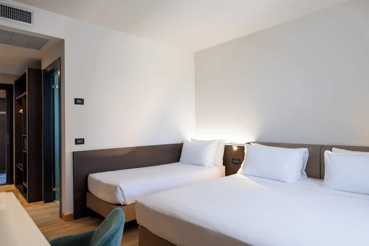 A hotel room with two beds, a desk, and a wardrobe.