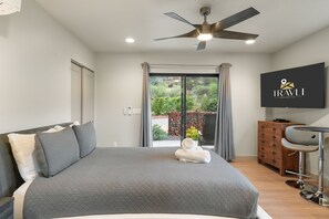Une chambre d’hôtel moderne dotée d’un grand lit, d’un ventilateur de plafond, d’une télévision et offrant une vue sur l’extérieur.