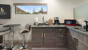 A modern kitchen with a window view, a bar area, and a mounted sign. - Moondance @ Oak Creek | Townhouse w/Views| FirePit (Sedona)