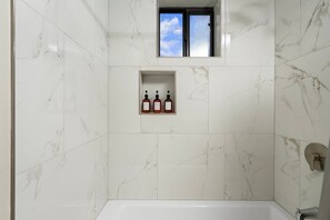 A bathroom with white marble tiles, a window, and a shelf with three bottles. - NEW|Oak Creek Retreat|Townhouse w/Views|FirePit (Sedona)