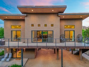 Un moderno edificio de dos plantas con tejado plano, ventanas amplias y un área exterior cubierta con asientos.