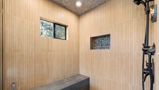 A modern shower area with vertical wooden paneling, a built-in bench, and a handheld showerhead. - Sycamore Canyon Luxe Retreat | 180° Views + Hottub (Sedona)