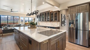 A spacious kitchen with a large island, stainless steel appliances, and a view of mountains through large windows. - Sycamore Canyon Luxe Retreat | 180° Views + Hottub (Sedona)