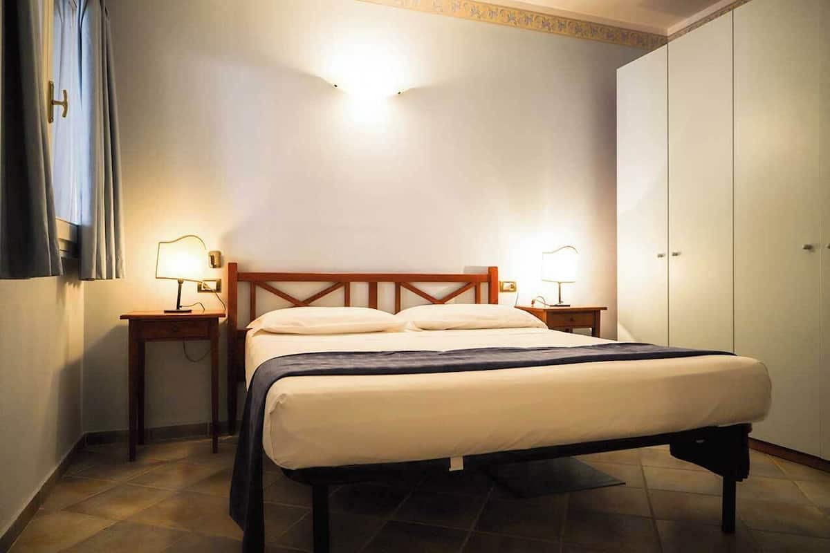 Una camera da letto con un letto, due comodini, un armadio e una lampada a soffitto.